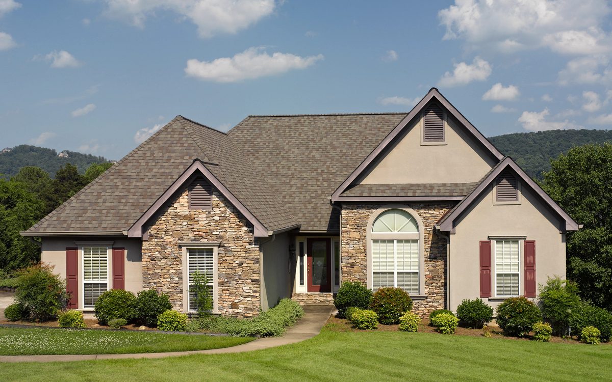 Home with a CertainTeed Landmark shingle roof, stone accents and red shutters