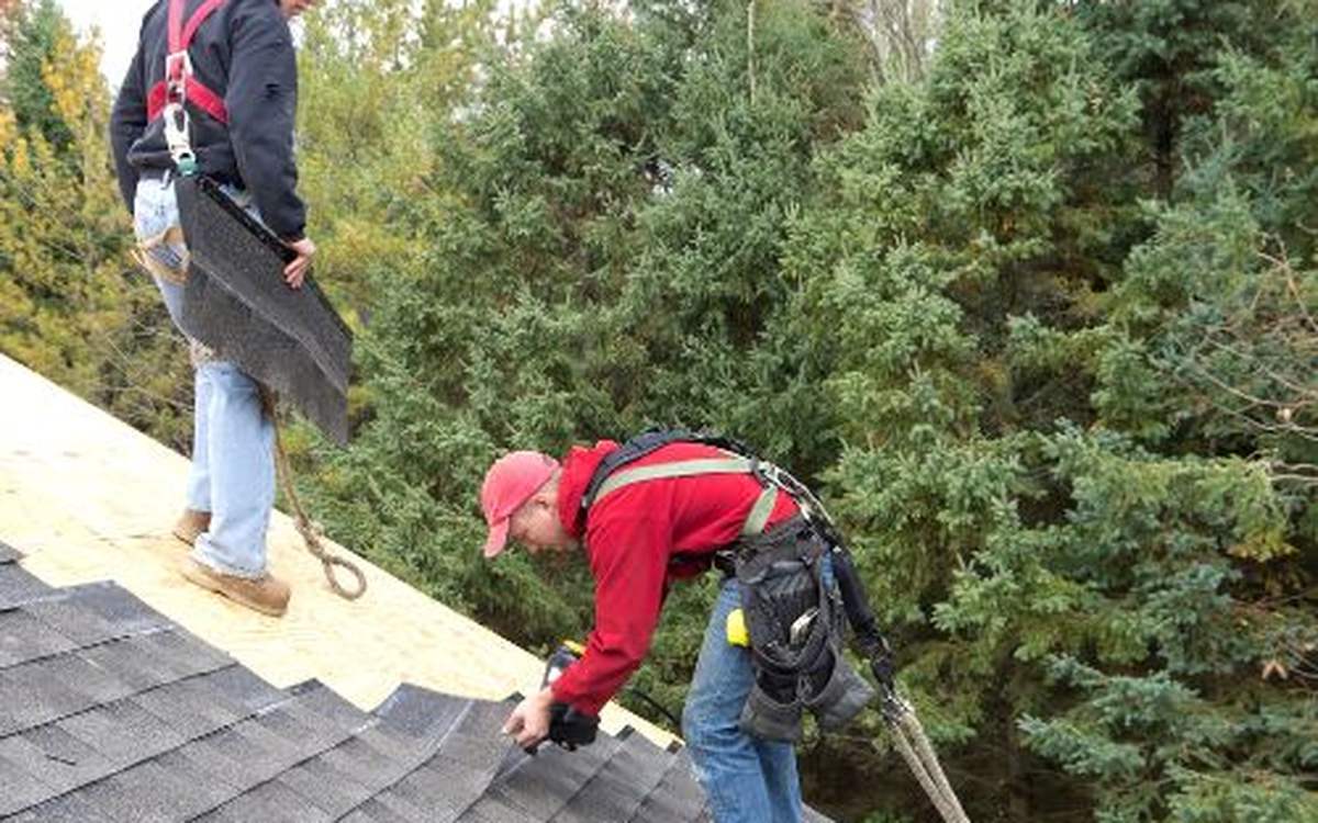 Roofing crew installing architectural asphalt shingles on a residential roof
